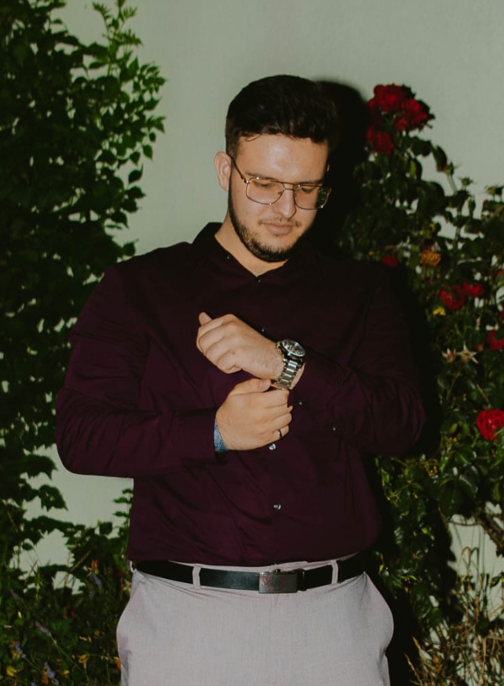 Emin Hodžić in a dark red shirt, adjusting his cuff